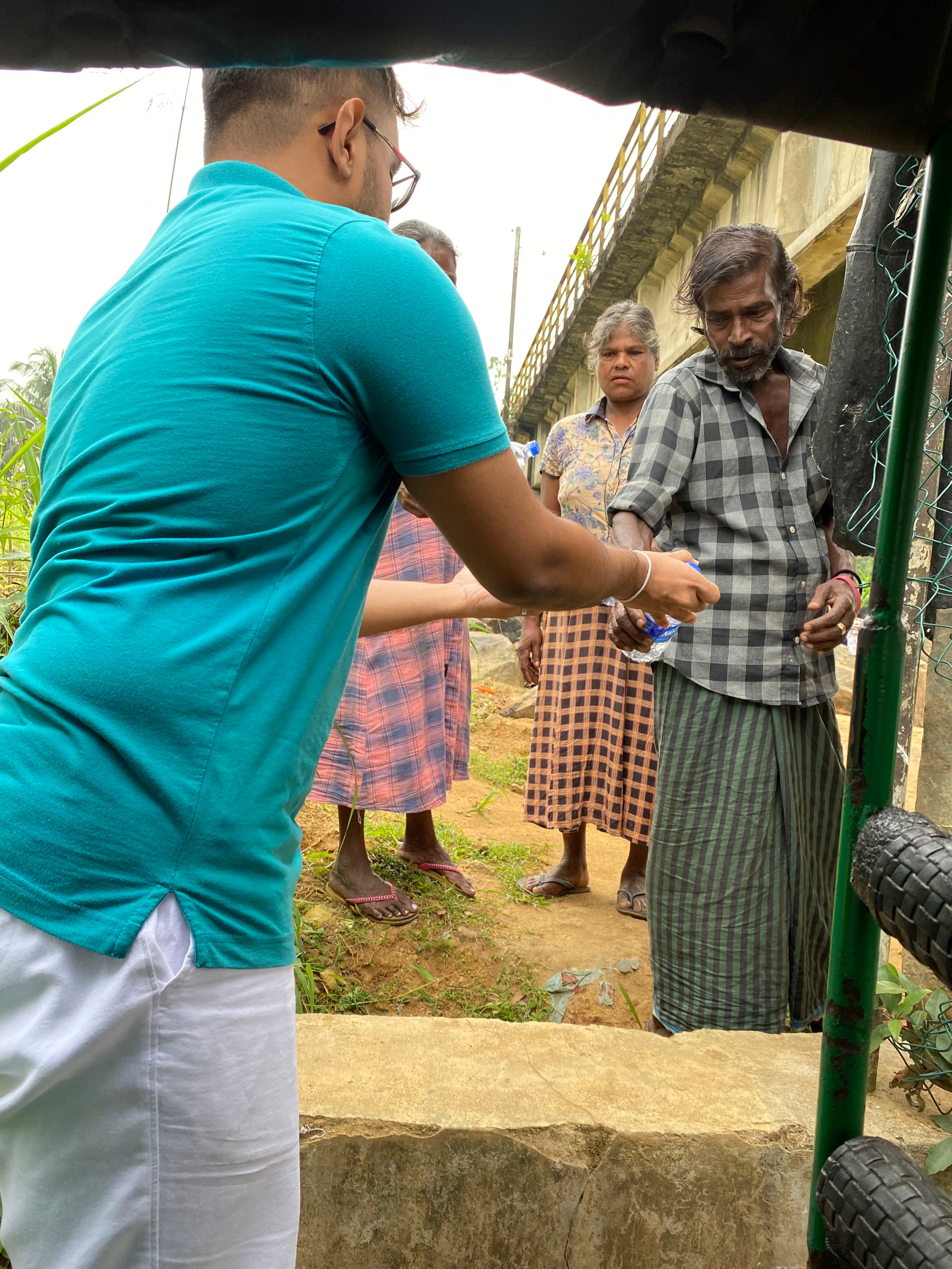 Ashan Veymont distributing water and food to community members outdoors