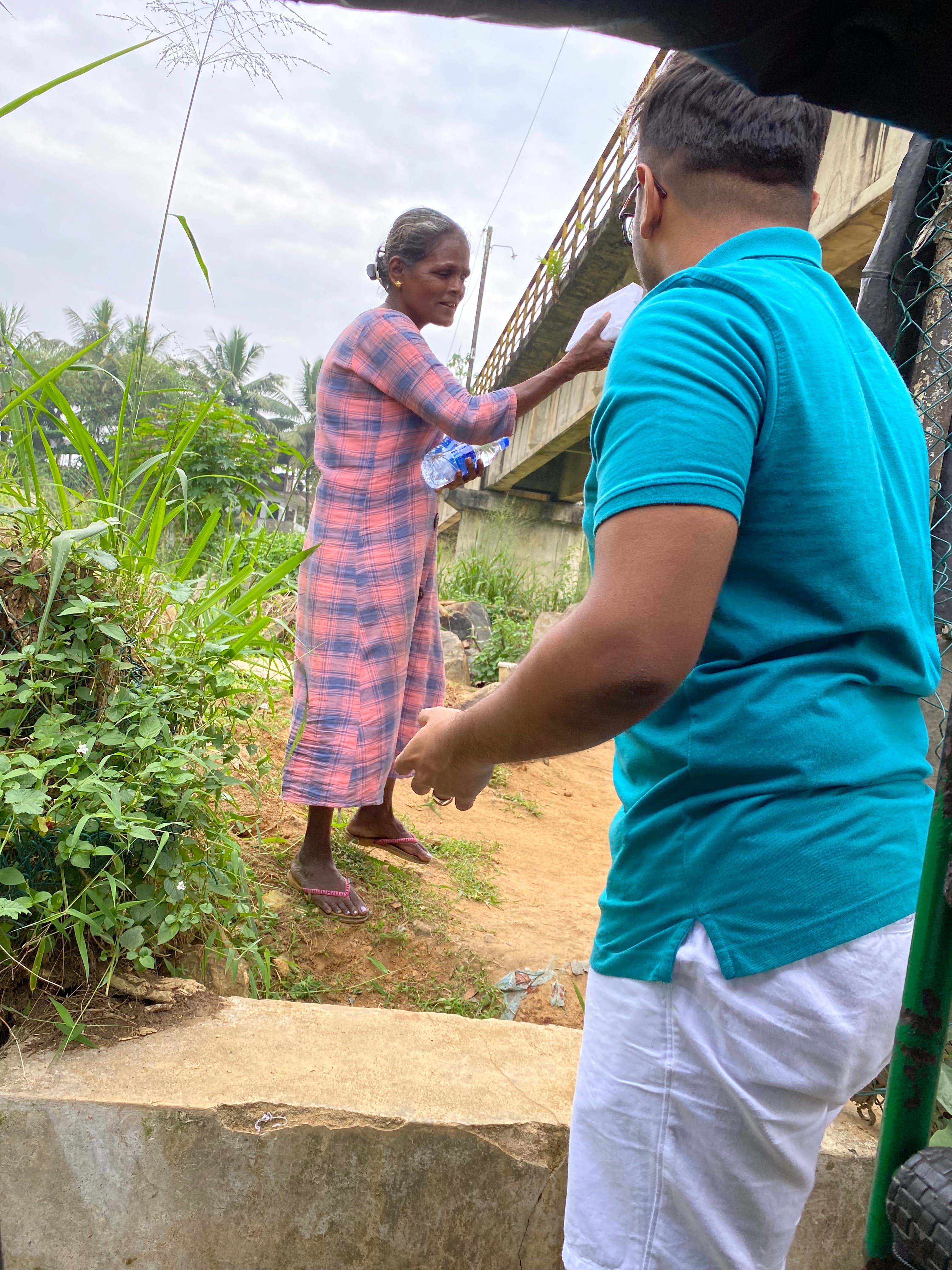 Ashan Veymont handing food packages to a woman during a community distribution